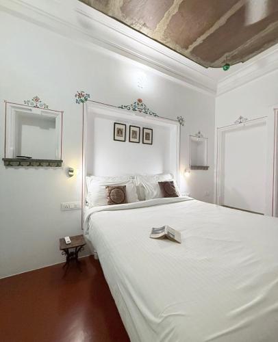 a bedroom with a large white bed with a tray on it at Little Garden Guest House in Udaipur