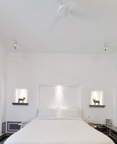 a bedroom with a white bed with two pictures of horses on the wall at Little Garden Guest House in Udaipur