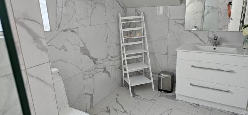 a bathroom with a marble wall with a ladder at Pyramid beach house in Karikari Peninsula