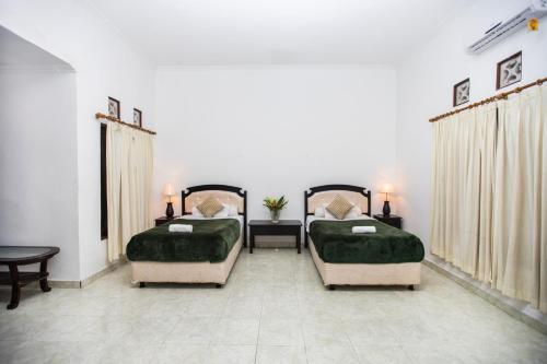 a bedroom with two beds with green covers and a table at Scoobydoo Bungalow in Nusa Lembongan