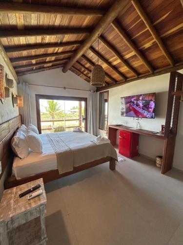 a bedroom with a large bed and a television at Kamaiurá Pousada in Caraíva