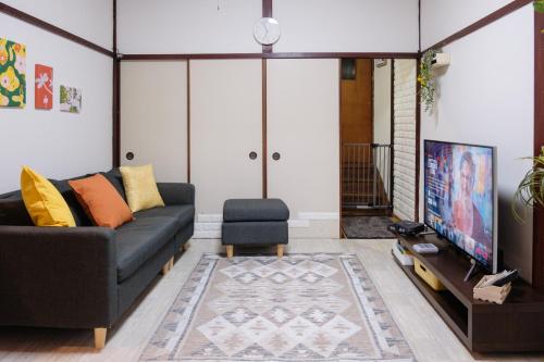 a living room with a couch and a tv at DK Matsunaga House in Fukuyama