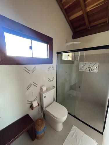 a bathroom with a toilet and a glass shower at Kamaiurá Pousada in Caraíva