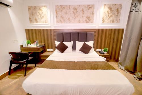 1 dormitorio con 1 cama grande, escritorio y ventanas en The Wedlock Hotel, en Gurgaon