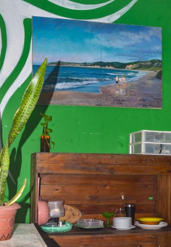 a green wall with a painting of a beach at Quarto Privativo Casal - Banheiro Compartilhado in Pipa