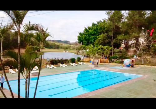 a swimming pool with chairs and a body of water at Cabaña Show Piscina Lagoa - Camping Carrion in Itu