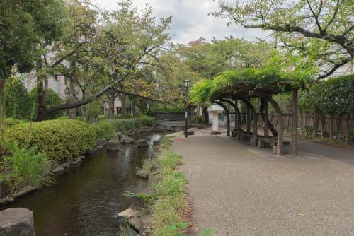 a walkway next to a river with benches and trees at 松島雅居 in Tokyo