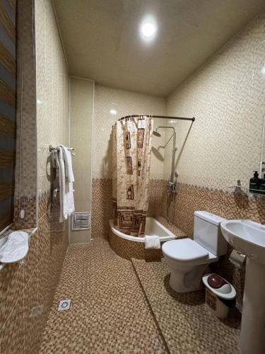 a bathroom with a toilet and a shower and a sink at Shuxrat hotel in Chilanzar