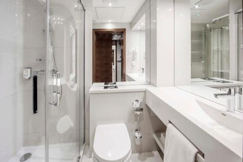a white bathroom with a toilet and a shower at Hotel Warszawianka in Jachranka