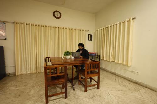 a woman sitting at a desk with a laptop at Rostel Backpackers Hostel in Pune