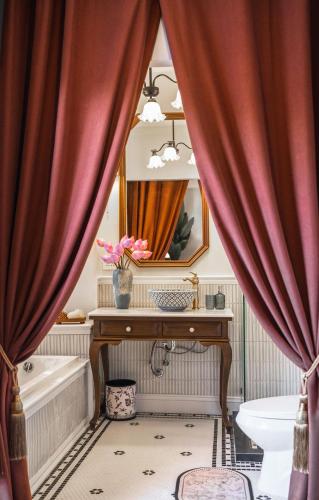 a bathroom with red curtains and a tub and a mirror at Maprang Boutique Stay in Nathon Bay