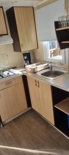 a kitchen with wooden cabinets and a sink at provence au pied du Luberon emplacement 325 domaine des iscles in La Roque-dʼAnthéron