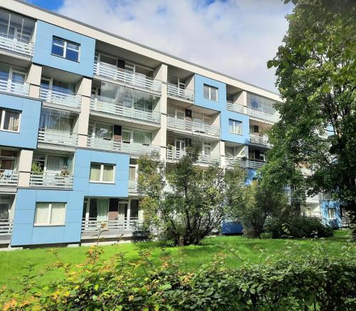 a blue apartment building with trees in front of it at Cozy 2-Bedroom flat with Terrace & Parking by Alfa in Rīga