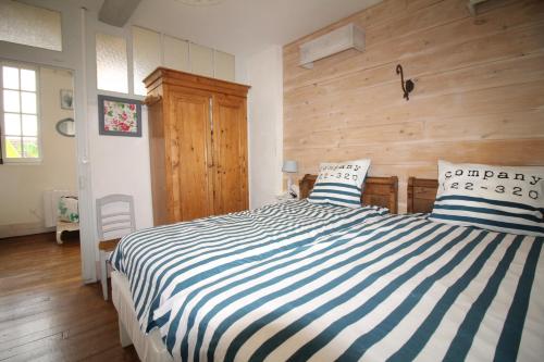 a bedroom with a large bed with blue and white stripes at le gîte de Claire maison avec terrasse, calme et confort, lit king size linge fourni in Couze-et-Saint-Front
