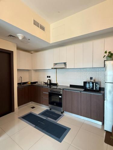 a large kitchen with white cabinets and a stove at Peaceful Cozy 1 BHK Pool Garden View Liwan Dubai Land in Dubai