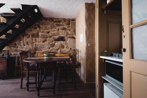 a dining room with a table and a stone wall at Casa dos Candeias - Apartamento Tio João in Chaves