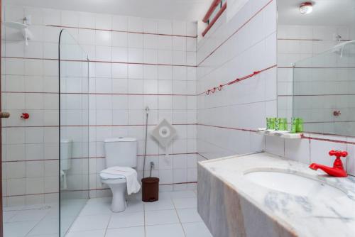 a white bathroom with a toilet and a sink at Pousada Barra Sol in Barra de São Miguel