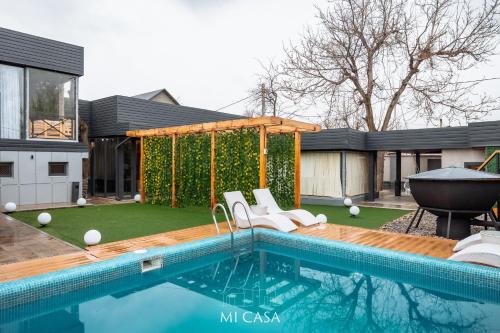 ein Haus mit einem Swimmingpool mit Stühlen und einem Garten in der Unterkunft Micasa residence in Schymkent