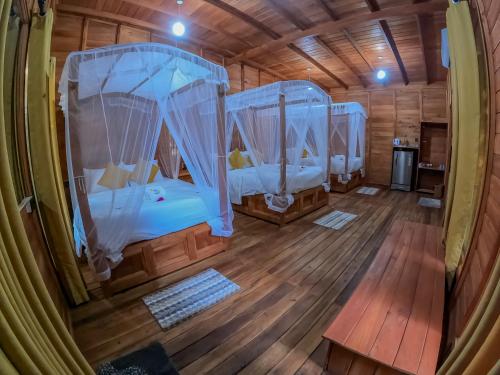 a room with three beds in a wooden cabin at Habarana Tree House Ambasewana Resort in Habarana