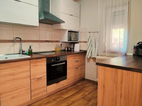 a kitchen with wooden cabinets and a sink and a stove at Csillag Vendégház Kiskunmajsa in Kiskunmajsa