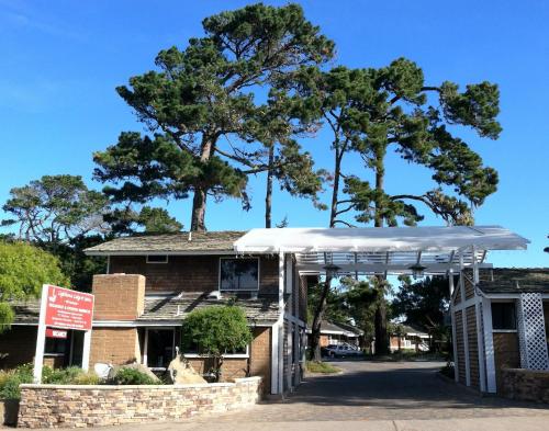 a white canopy in front of a building with trees at Lighthouse Lodge & Cottages in Pacific Grove