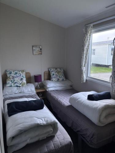 two beds in a room with a window at Tigh na Mara in Padstow