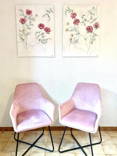 two pink chairs in a room with paintings on the wall at Studio des fleurs in Céret