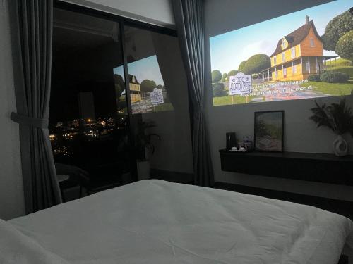 a bedroom with a large window with a poster of a house at Famille Hotel - Central hotel in Dalat in Xuan An