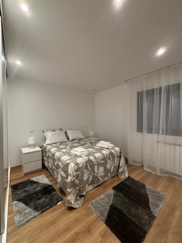 a white bedroom with a bed and two rugs at Casa de Arcas in Terras de Bouro