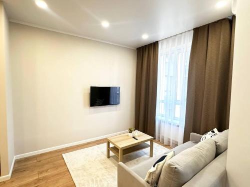 ein Wohnzimmer mit einem Sofa und einem Fernseher an der Wand in der Unterkunft ЦЕНТР ГОРОДА & PERFECT APARTMENT & CENTER OF THE CiTY in Almaty