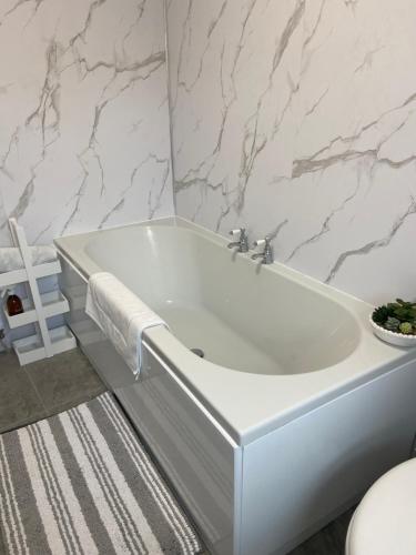 a white bath tub in a bathroom with marble walls at Old Store Cottage, Up Holland in Upholland