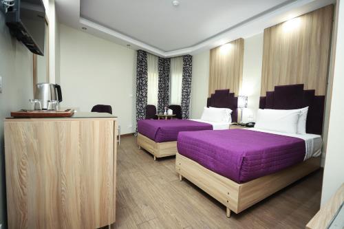 ein Hotelzimmer mit zwei Betten mit lila Bettwäsche in der Unterkunft Gawharet Al Ahram Hotel in Kairo
