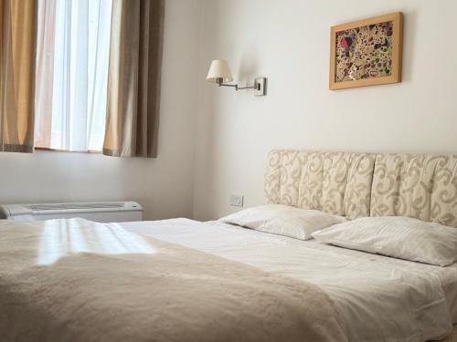 a bedroom with a white bed with a headboard and a window at Jaram Vile Apartmani in Kopaonik