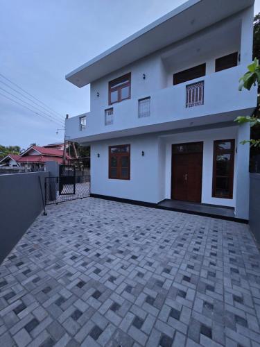 une maison blanche avec une allée en briques dans l'établissement N A 63 Residence Transit Hotel, à Negombo