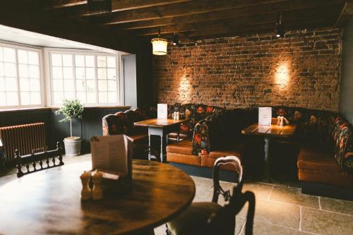 a restaurant with tables and couches and a brick wall at Le Petit Chateau & William de Percy in Otterburn