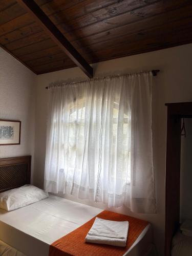 a bedroom with a bed and a window with white curtains at Hotel Villar in Penedo