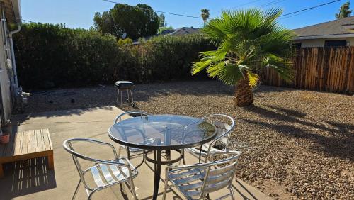 a glass table and chairs in a yard with a palm tree at zzz Msg for 5 percent off zzz 3Bed 1Bath KingKingQueenBeds House MidtownPHX in Phoenix