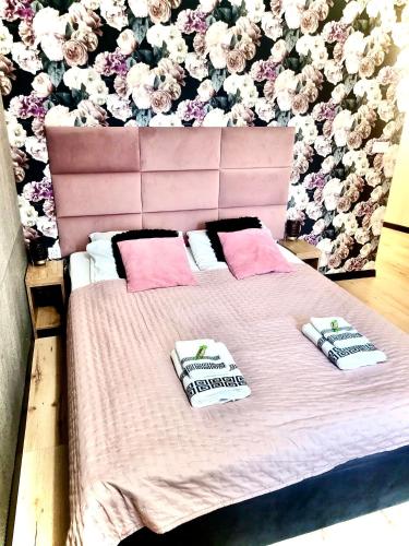 a bed with two pillows and a wall with flowers at Apartament w sercu Elbląga in Elblag
