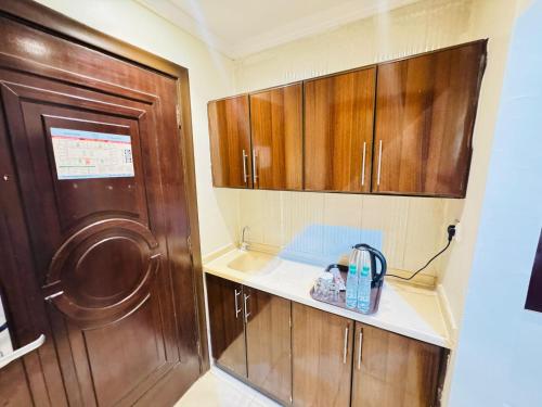 mała kuchnia z drewnianymi szafkami i zlewem w obiekcie Rafahya Hotel 2 w Mekce