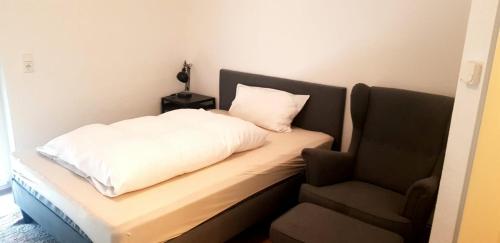 a bed with a white pillow and a chair at A & M Apartments in Hildesheim