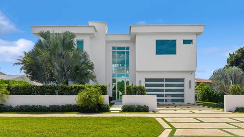 a white house with a palm tree in front of it at Luxury New Modern Beach Mansion in BEST Location! in Jupiter