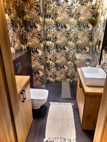 a bathroom with a sink and a toilet and a wallpaper at Apartament w sercu Elbląga in Elblag