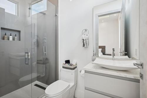 a white bathroom with a toilet and a sink at Luxury New Modern Beach Mansion in BEST Location! in Jupiter