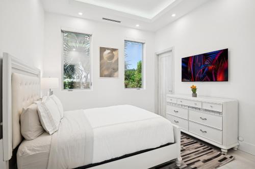 a white bedroom with a bed and a dresser at Luxury New Modern Beach Mansion in BEST Location! in Jupiter