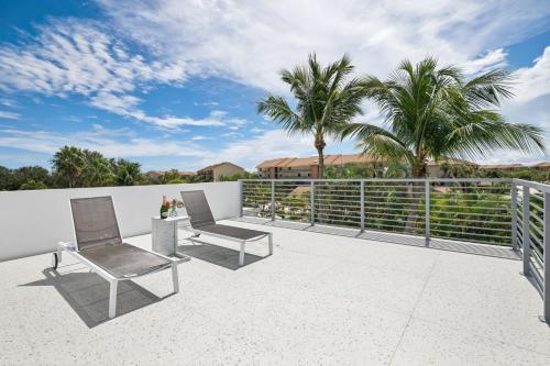 a patio with two chairs and palm trees at Luxury New Modern Beach Mansion in BEST Location! in Jupiter