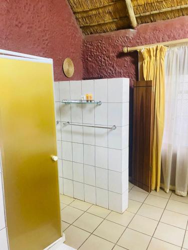 a bathroom with a shower with a yellow door at Xisaka Guest House in Giyani