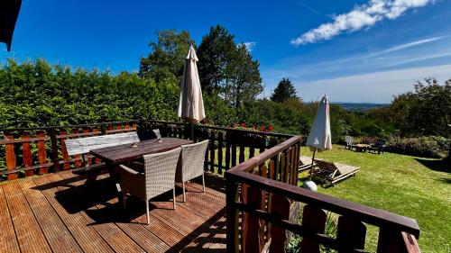 een houten terras met een tafel en een parasol bij Die Waldstube in Bromskirchen