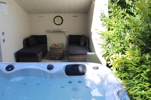 a jacuzzi tub with a couch and a clock at Ô Rethel Jacuzzi, Gîte Ardennes in Rethel