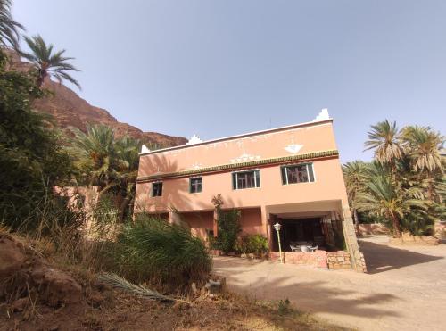 a building with palm trees in front of a hill at Le LAC Auberge Camping Todra in Tinerhir