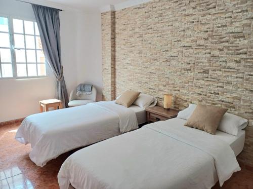 a bedroom with two beds and a brick wall at Guesthouse El arca de Noé in Pozo Izquierdo